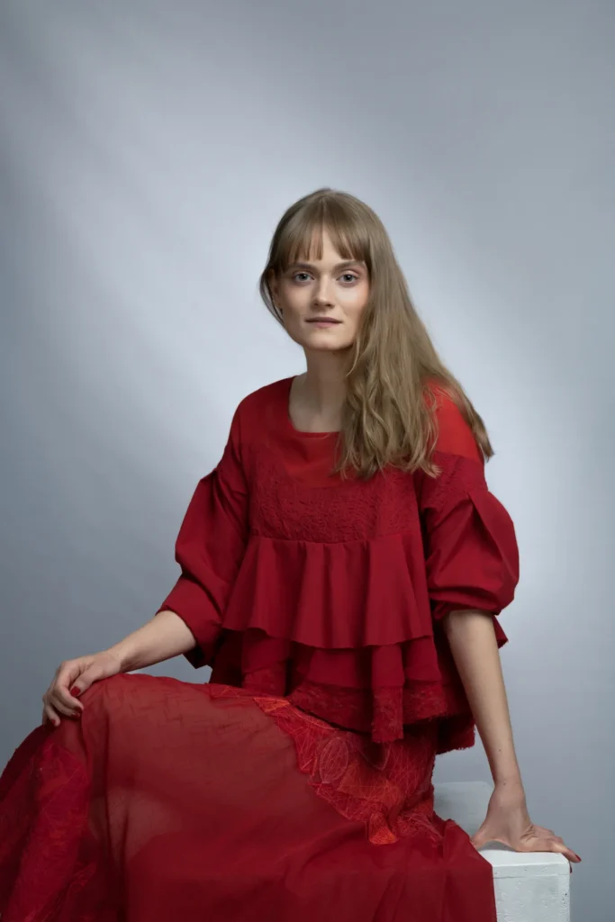 Portfolio aktorskie - portret młodej kobiety w czerwonej sukience. Kobieta aktorka - patrzy spokojnie w obiektyw. Fotograf Natalia Rakowska